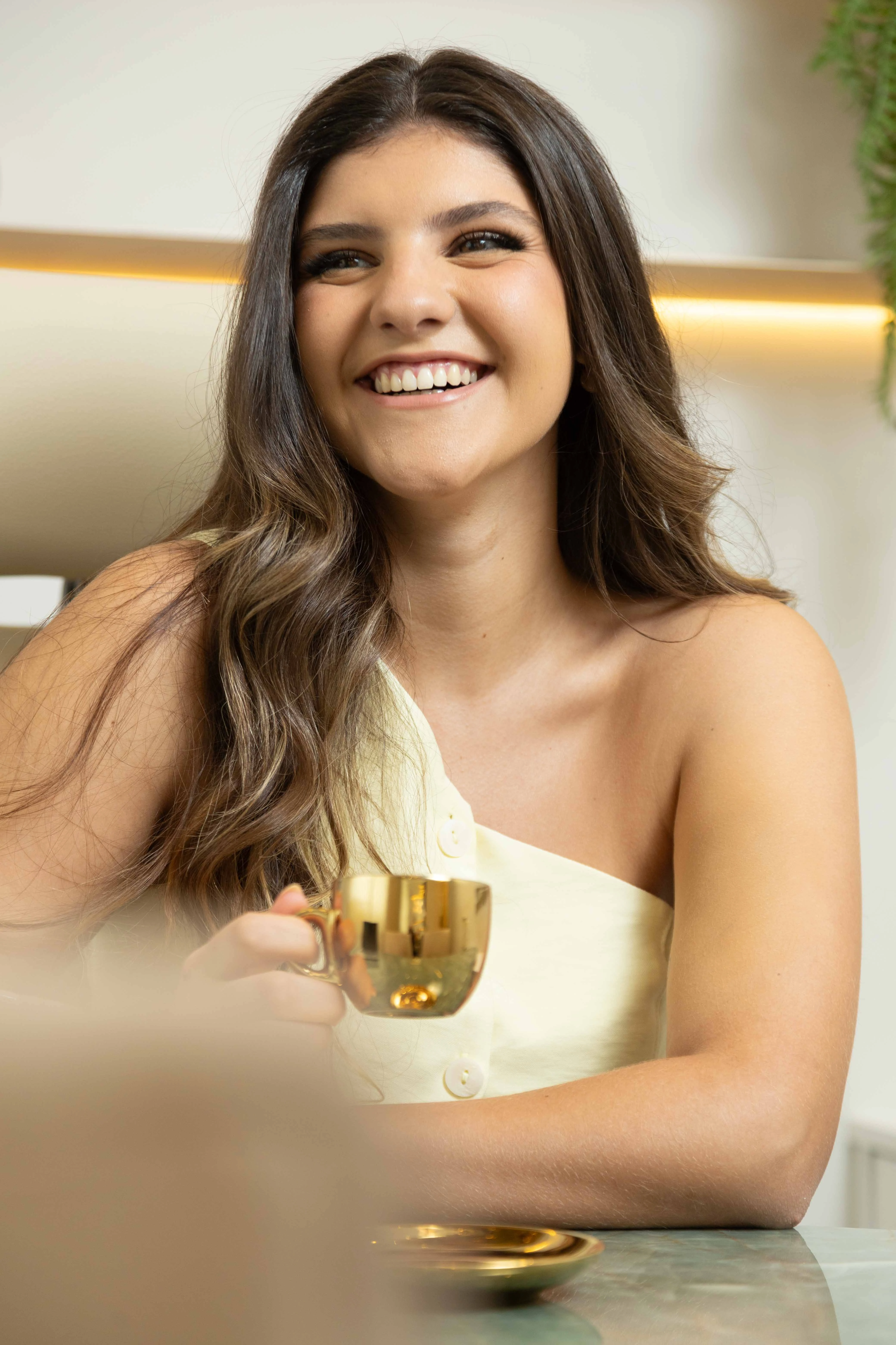 Sol Poretti sorrindo acolhedora à mesa de atendimento em seu consultório em Maringá.